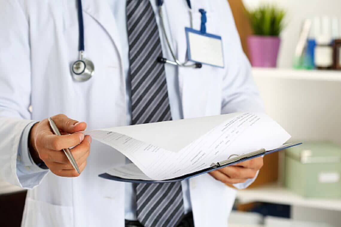 Doctor holding a clipboard and pen in a bright clinic office