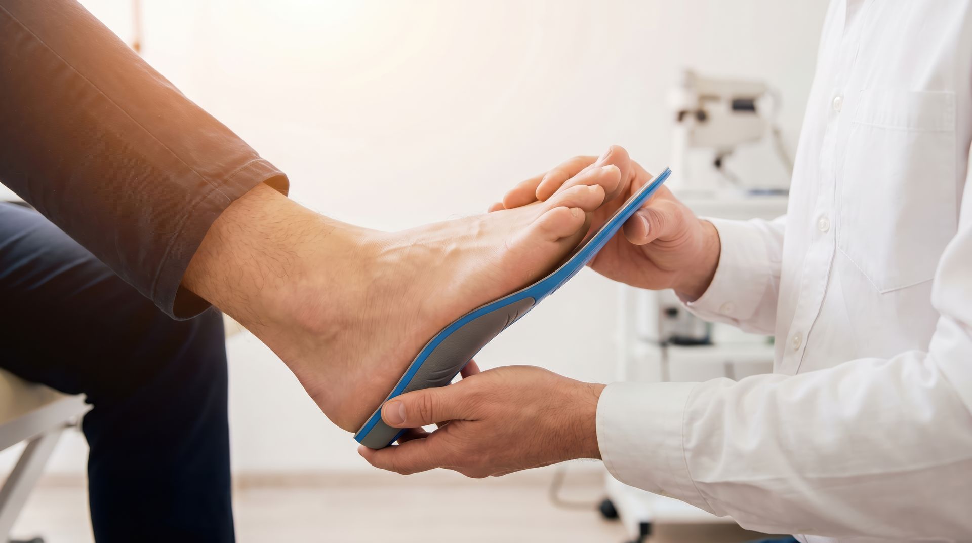 Healthcare worker measuring a patient’s foot with a blue tape measure on a white exam table