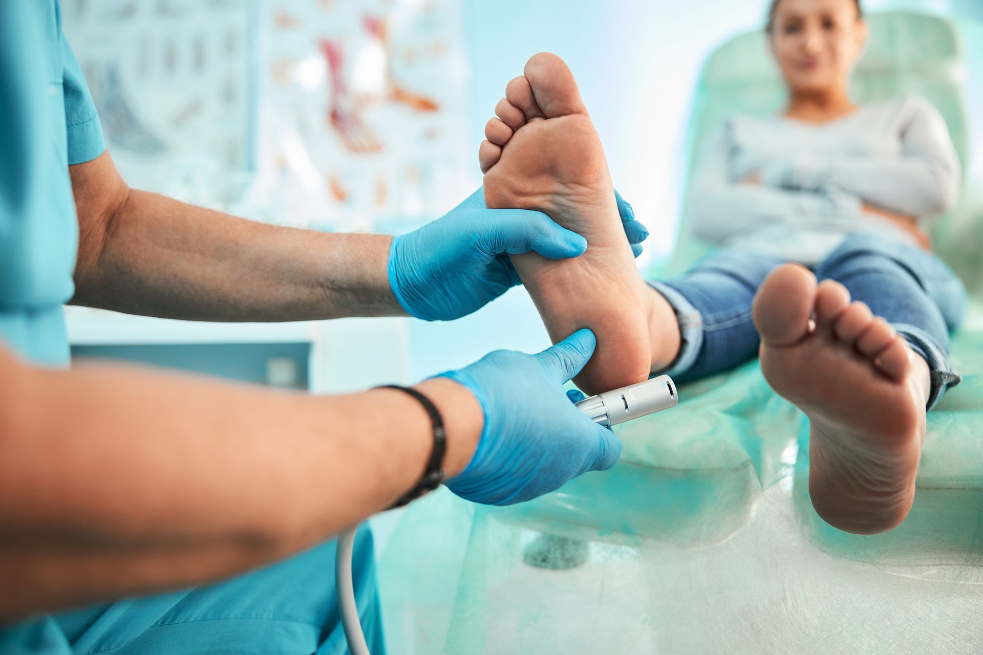 Clinician gloved hands examine a patient’s feet in a bright medical setting