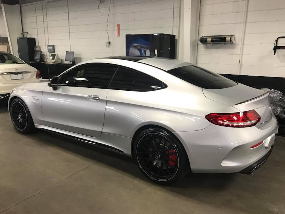 Silver Mercedes-Benz C-Class coupe in a garage, black wheels, red brake calipers.