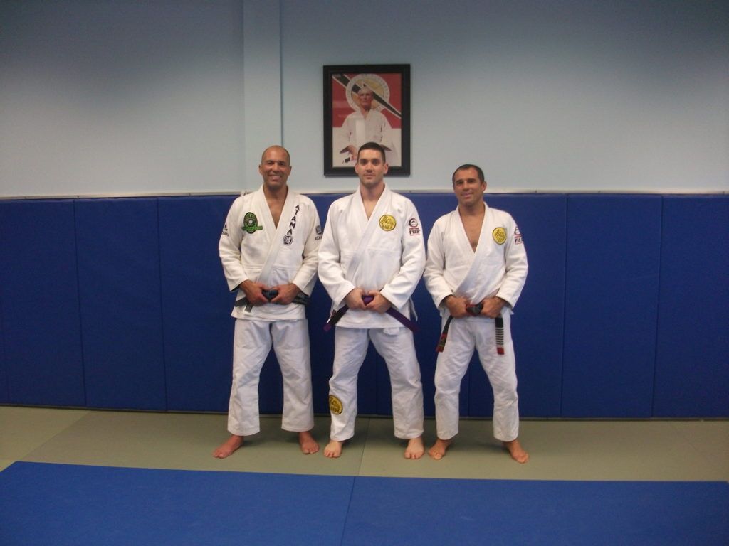 Three men in white karate uniforms are posing for a picture