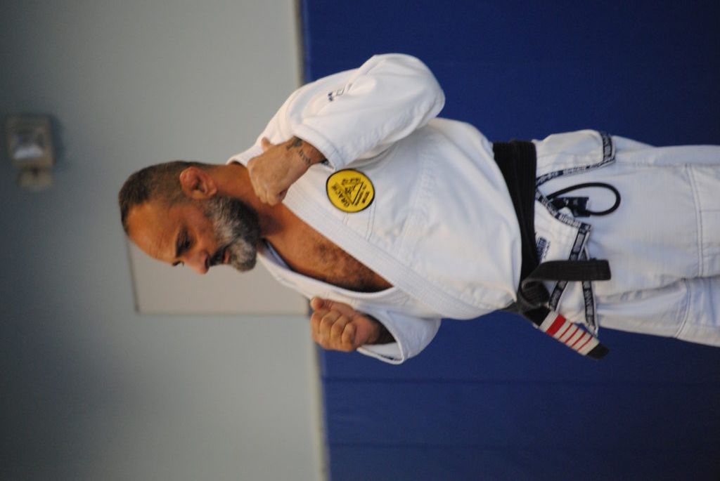 A man with a beard is wearing a white karate uniform