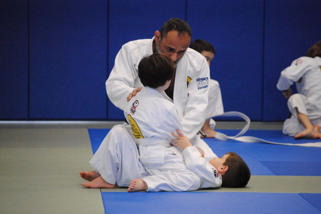 A man is teaching two young boys how to do judo