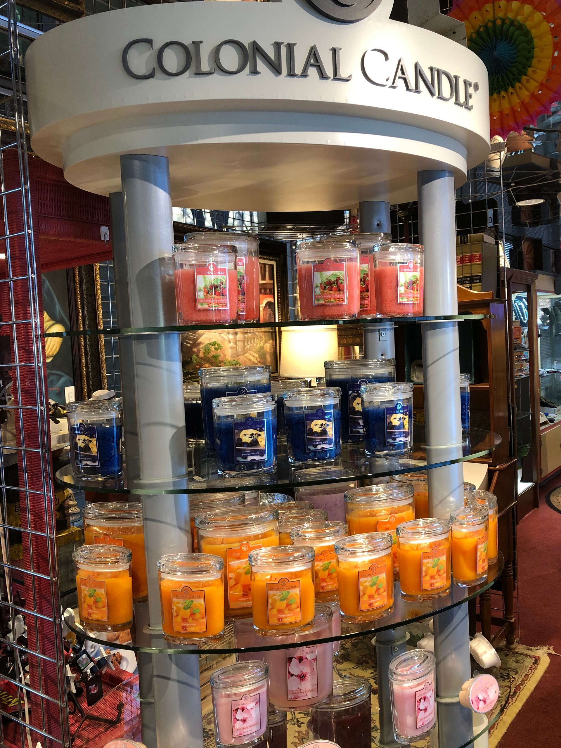 Colonial Candle display rack with colorful scented candles in a store