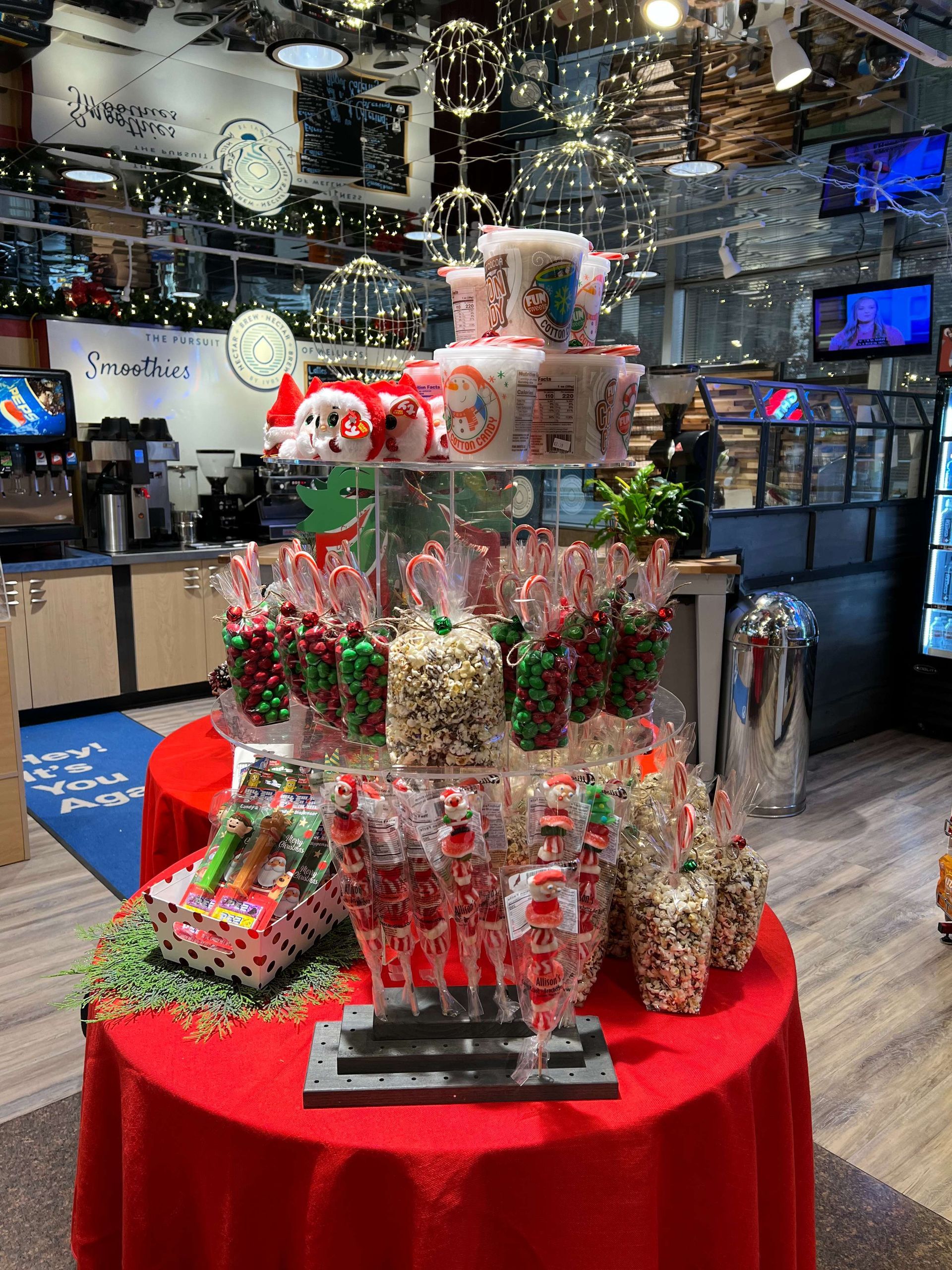 Gift display on a red table in a store, with festive holiday bags, ornaments, and decorations.