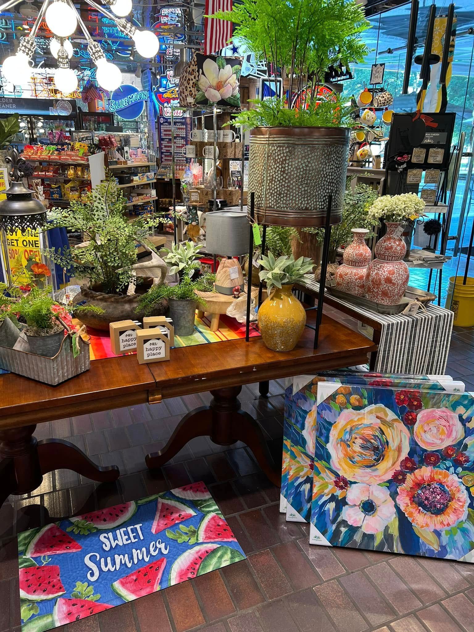 Colorful flower and gift display on a table in a shop, with bright decor and wrapped presents nearby