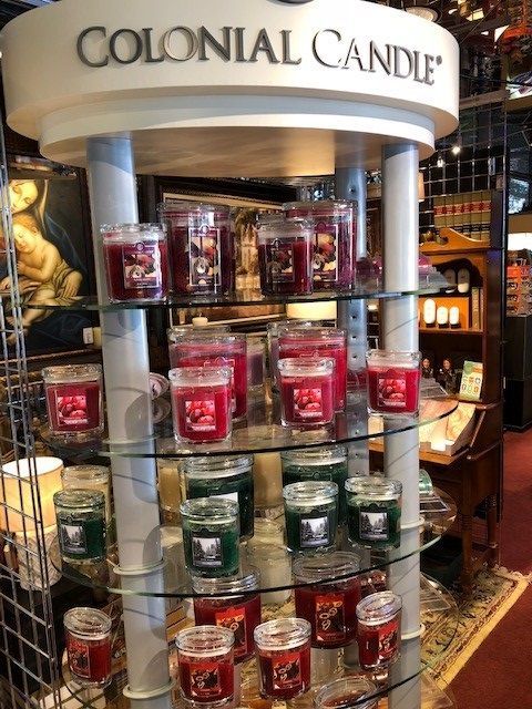 Colonial Candle display with rows of colorful scented candles in a store kiosk