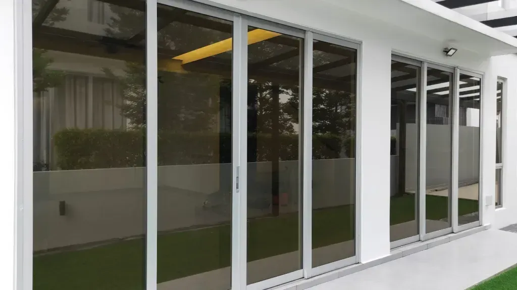 A white house with a lot of windows and sliding glass doors.
