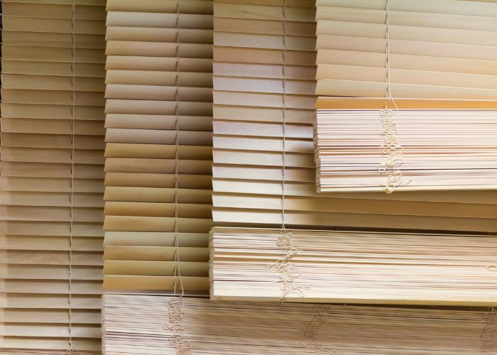 A stack of wooden blinds sitting on top of each other on a wooden floor.