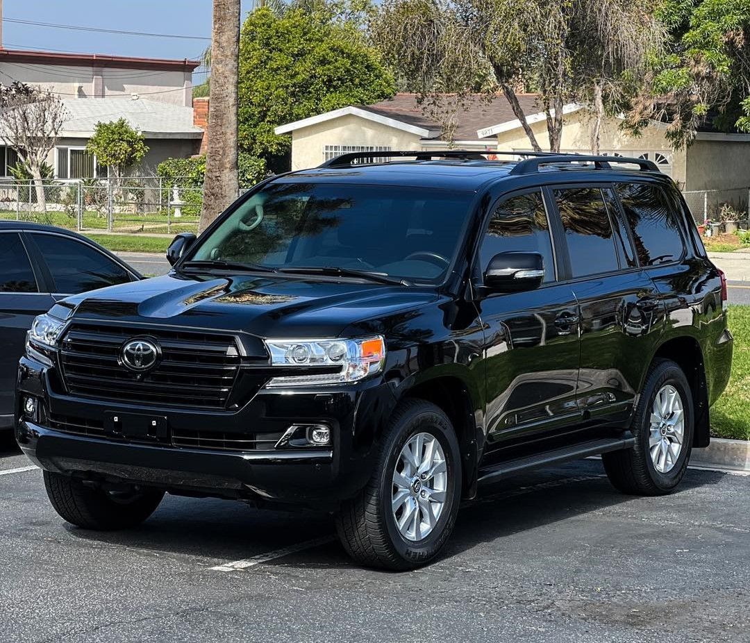 Black Toyota Land Cruiser parked on a street in front of a house.