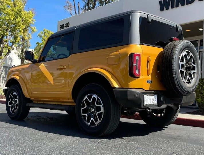 Yellow off-road SUV parked outside a building, with a rear spare tire and black roof.