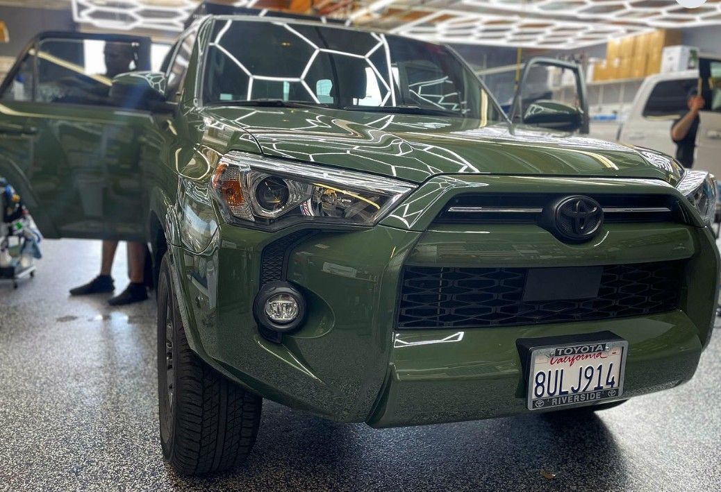 Green Toyota SUV indoors with doors open and a person visible in the background