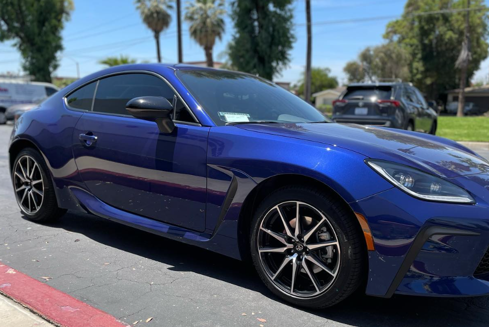 Blue sports coupe parked on a sunny street near palm trees
