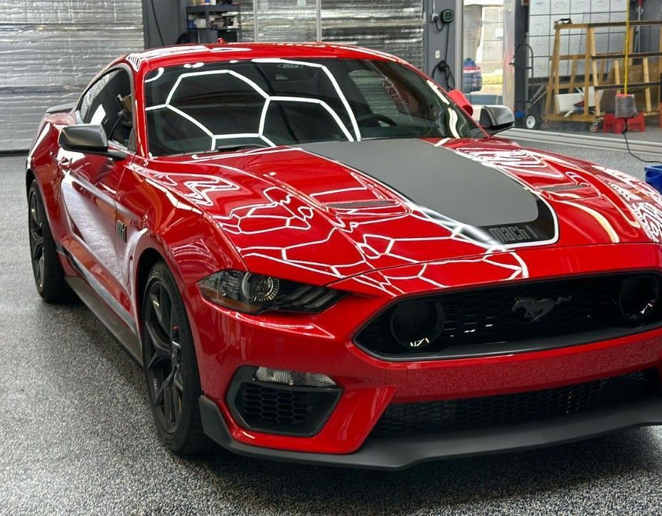 Red Ford Mustang Mach-1 with black accents, parked in a garage.
