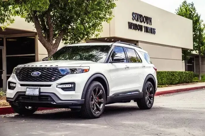 A white ford explorer is parked in front of a building.