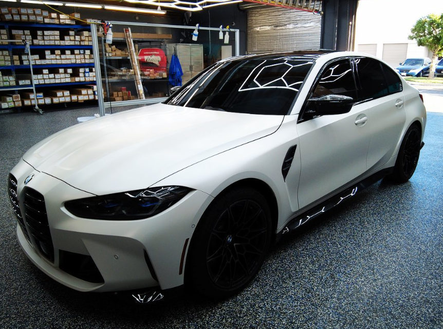 White BMW coupe with black wheels parked indoors in a garage