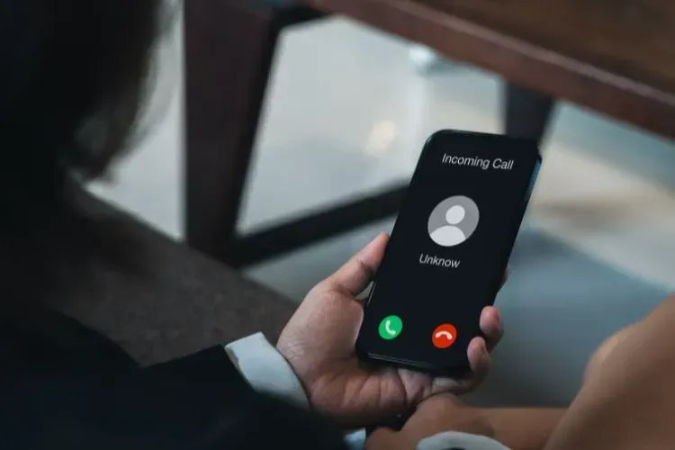 A person is holding a cell phone with a ringing call on the screen.