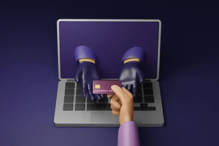 A person is holding a credit card and typing on a laptop.