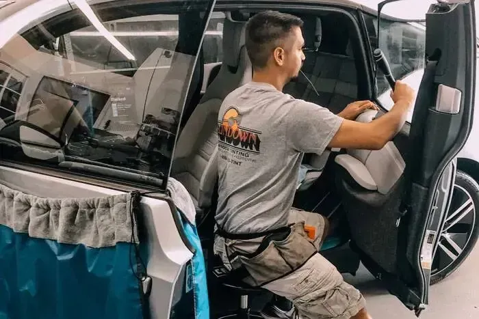 A man in a wheelchair is working on the interior of a car.