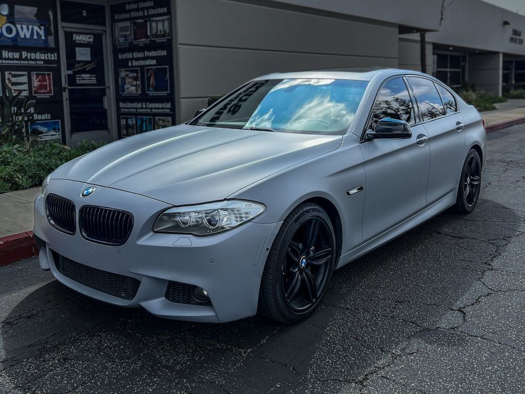 A silver bmw is parked in front of a building.