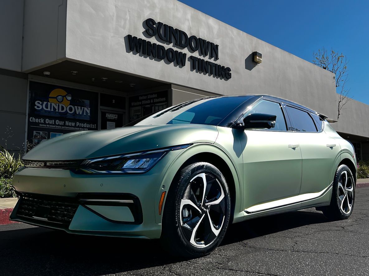 A green car is parked in front of a building.