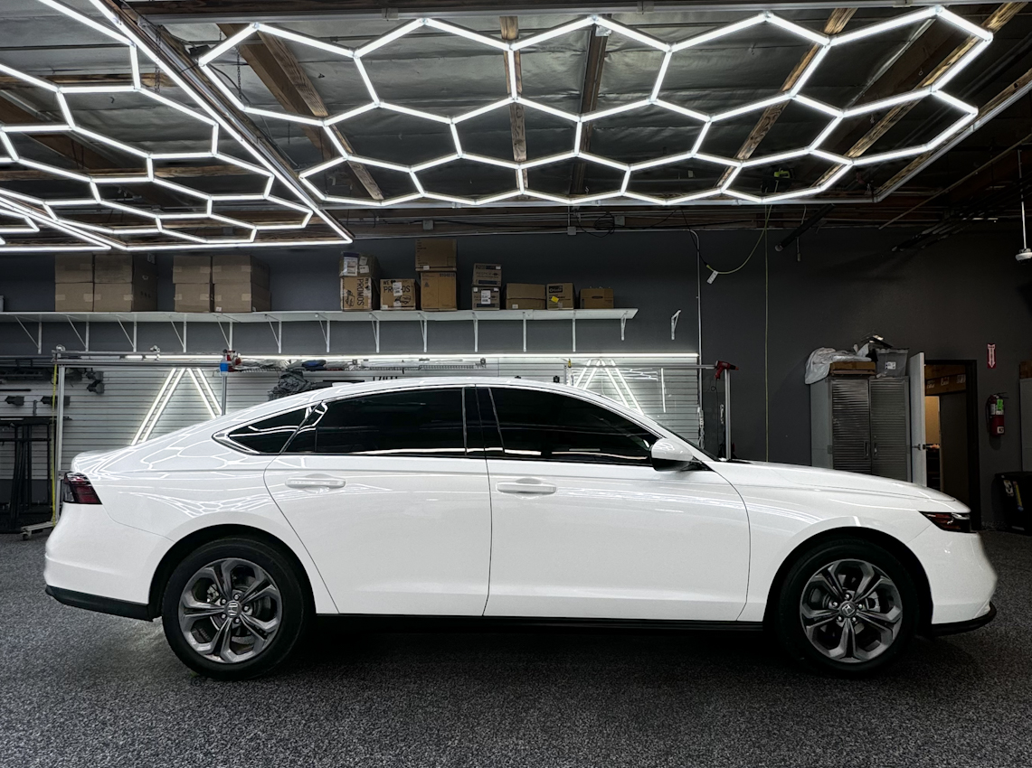 White SUV in a showroom with geometric ceiling lights and a glossy dark floor