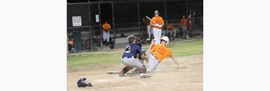 Baseball glove with ball on green grass, with blurred baseballs in the background.