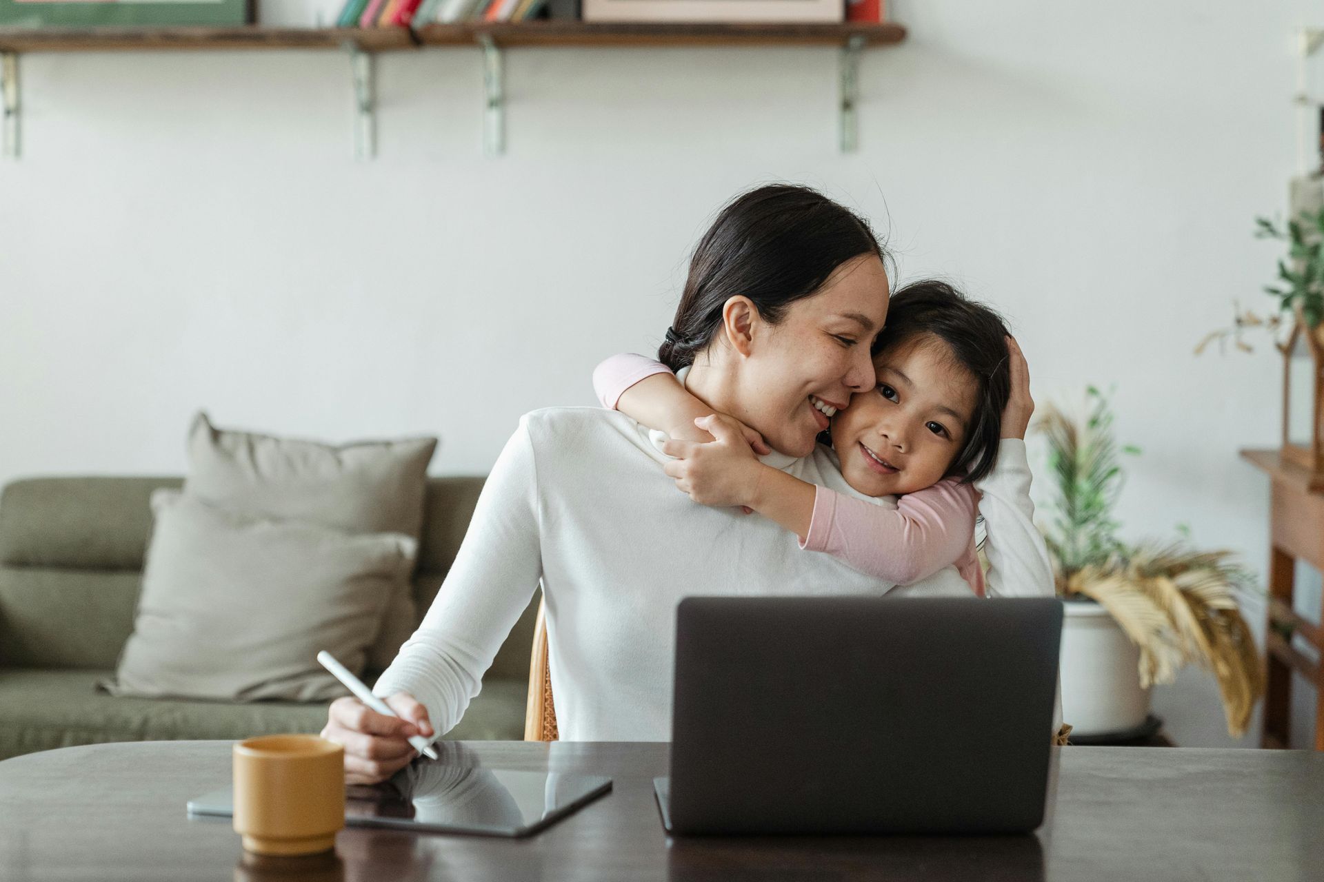 Two women are sitting on a couch looking at a tablet.