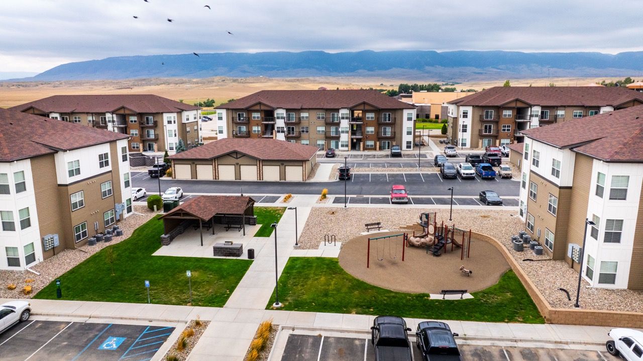 Aerial view of a multi-building apartment complex with a central courtyard, playground, and parking.