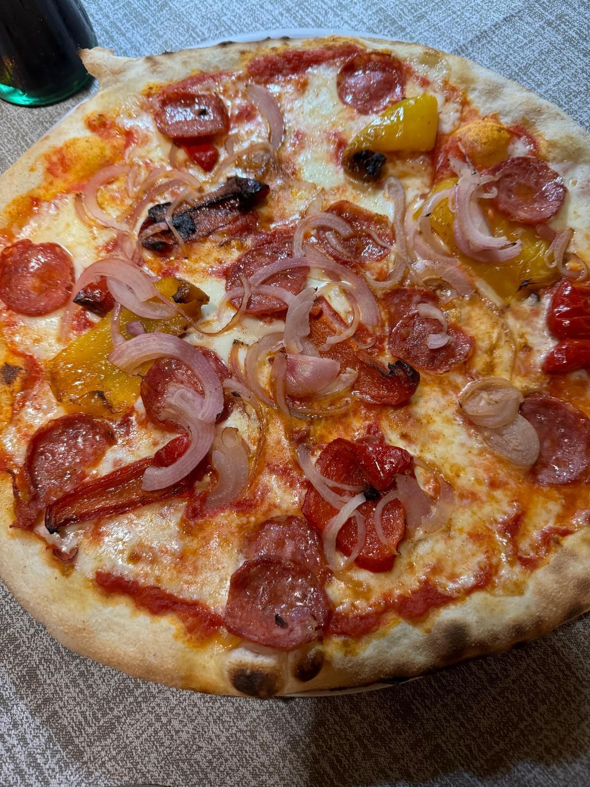 Pizza con peperoni e cipolle, formaggio fuso e peperone giallo su un piatto