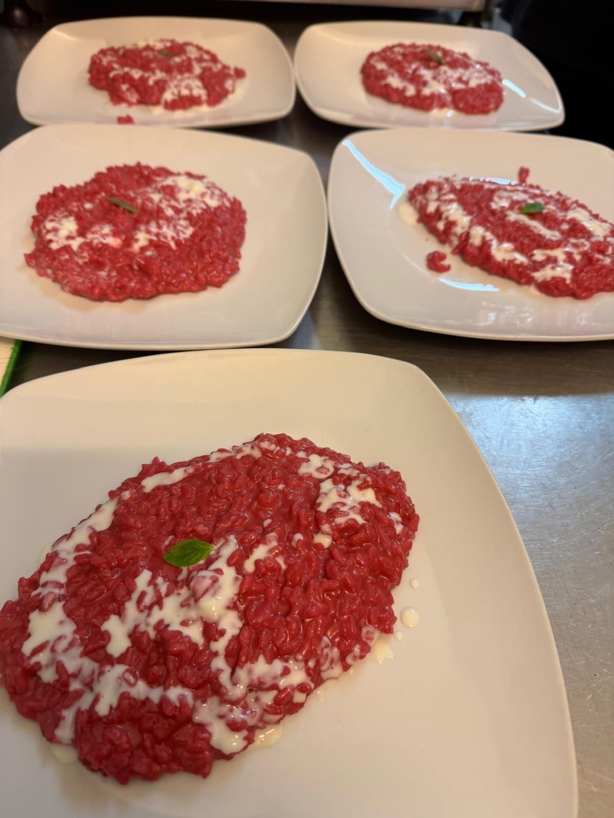 Cinque piatti di risotto alla barbabietola rossa guarniti con formaggio bianco su un tavolo