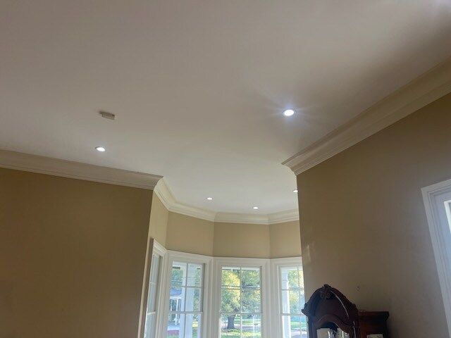Bright beige room with recessed ceiling lights, bay window, and a coat rack near the corner.
