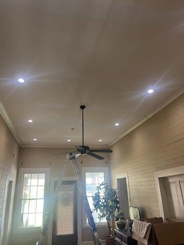 Bright living room with high ceiling, ceiling fan, recessed lights, and tall windows