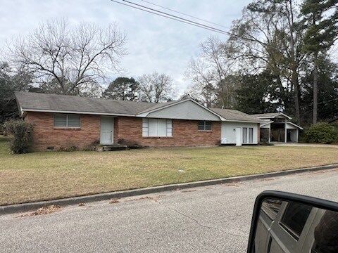 Single-story brick house with white trim and carport on a quiet suburban street
