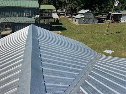 Corrugated metal rooftops in a rural yard with green buildings and grass