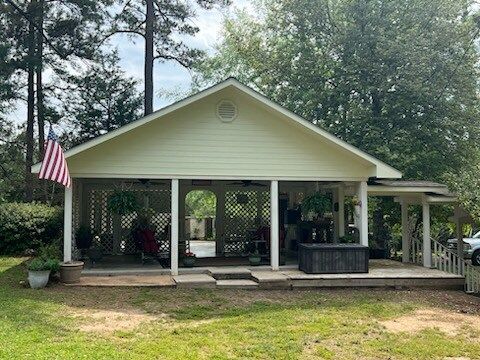 Small white porch house with an American flag and trees in the yard
