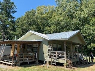 Two small cabins with porches and ladders in a wooded area under a blue sky