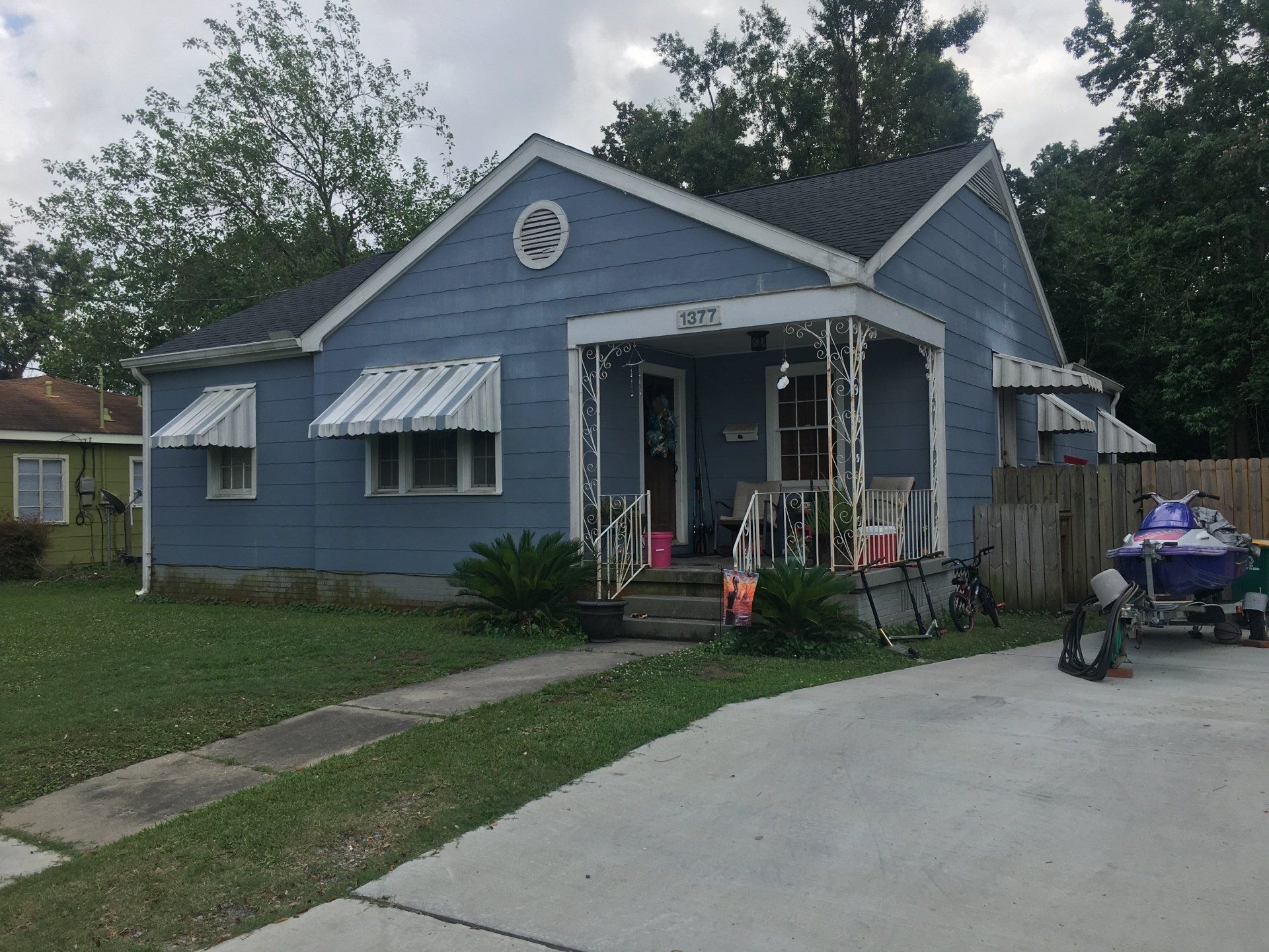 Blue single-story house with white trim, small porch, and driveway in a residential neighborhood