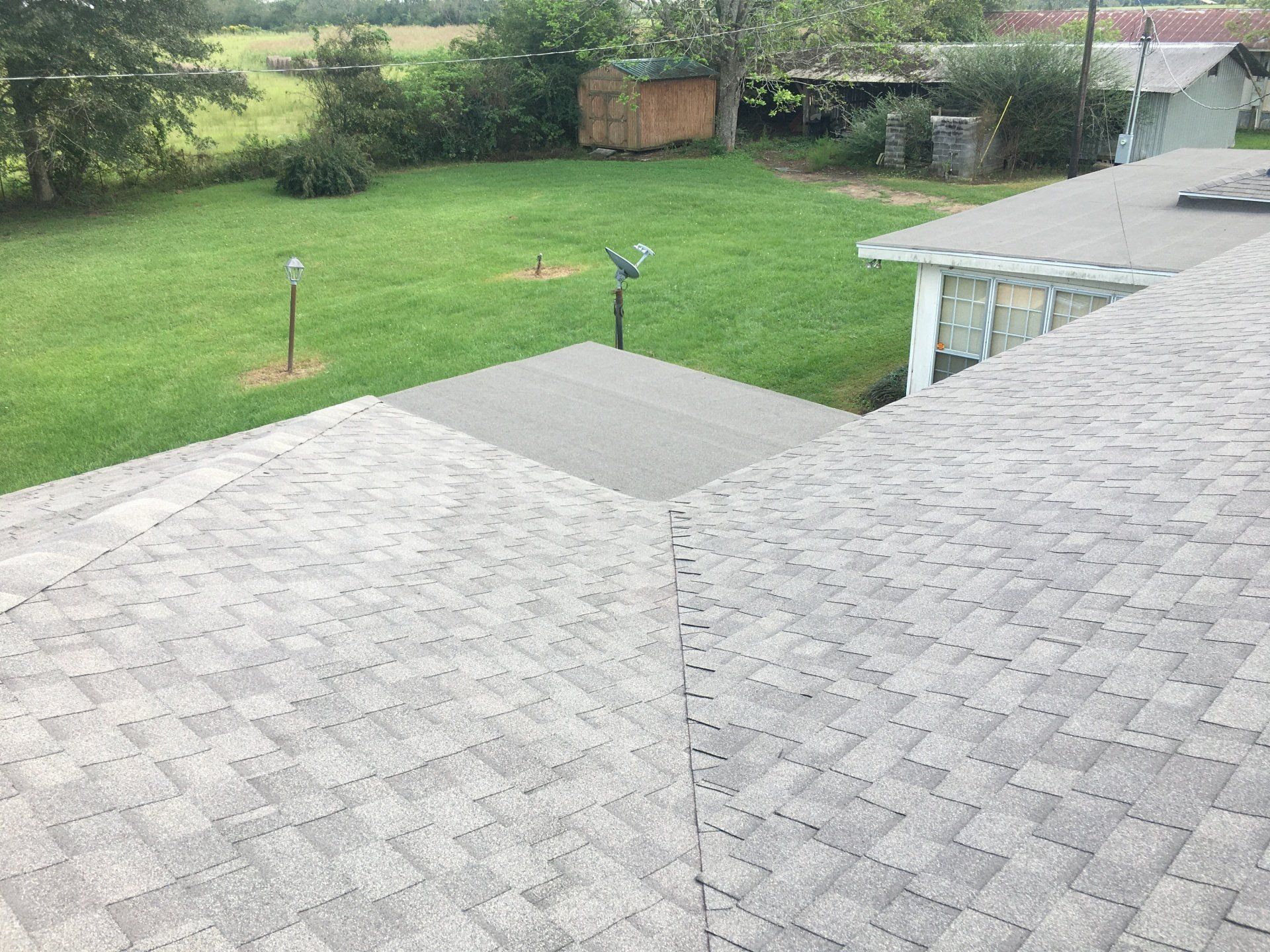 Gray shingle roof overlooking a green backyard with a few garden lights and a small shed