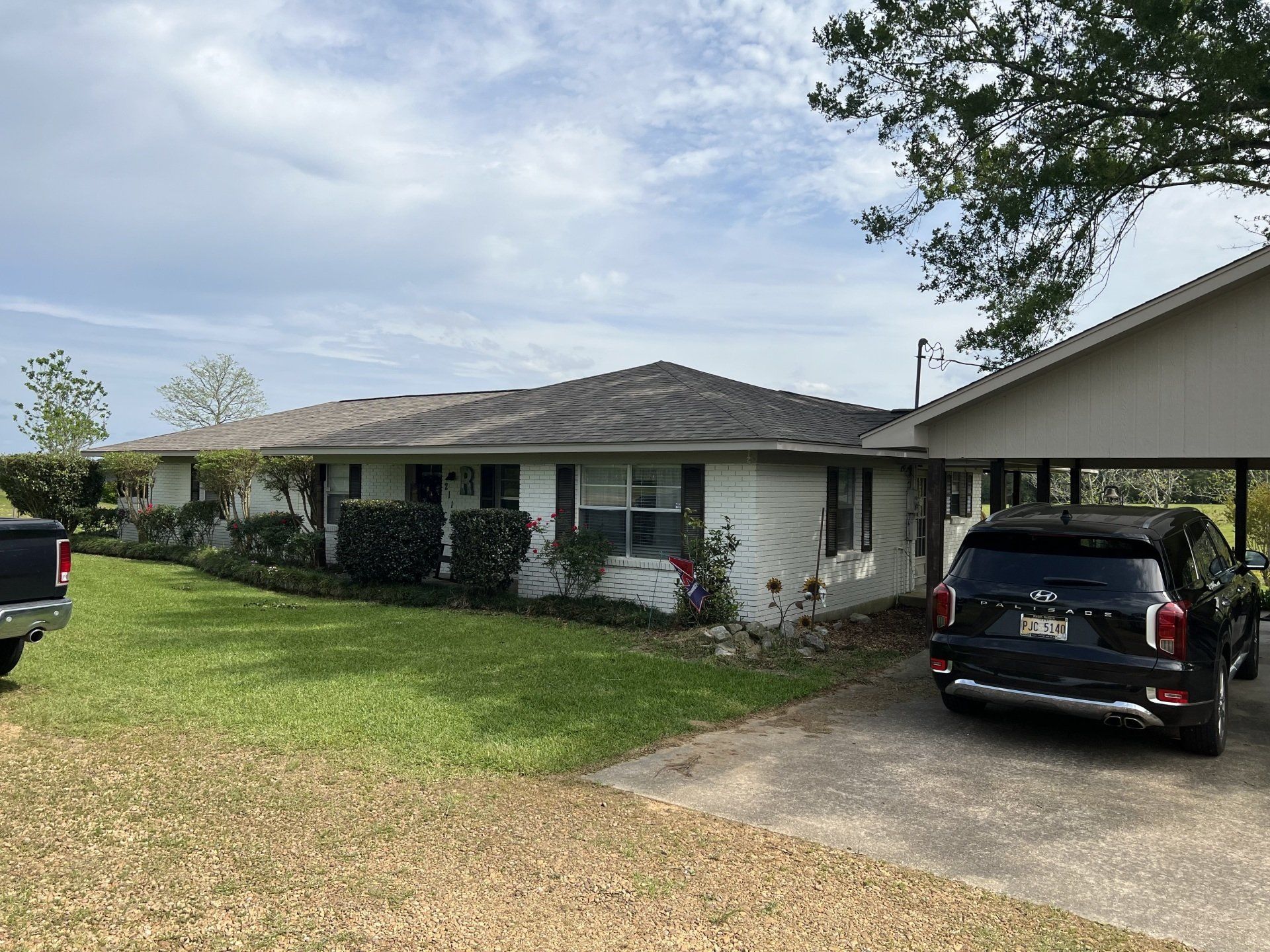 Single-story house with a front lawn and a black SUV parked in the driveway under a cloudy sky