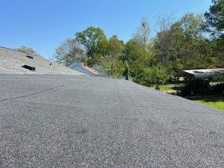 Roof shingles on a house with trees and blue sky in the background