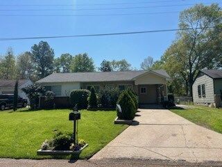 Single-story house with a front lawn, mailbox, and driveway under a clear blue sky