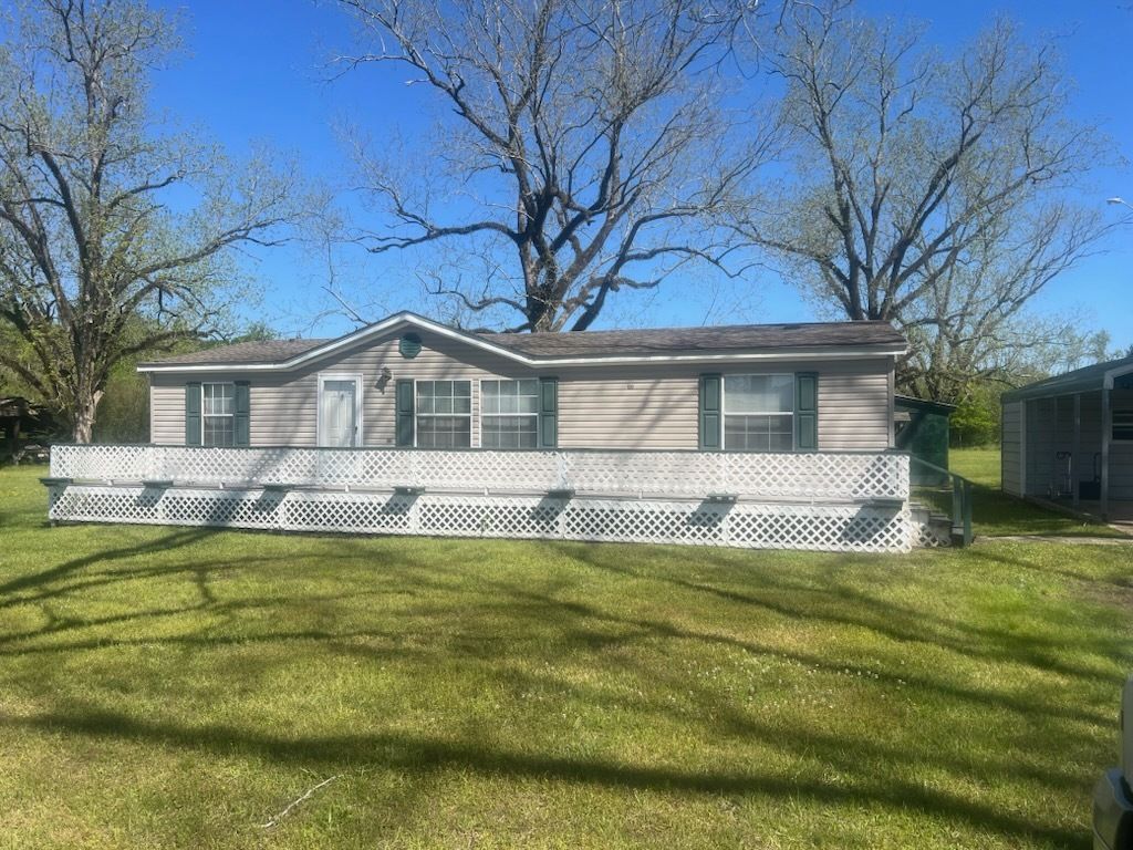 Single-story white house with a large front porch and a grassy yard under bare trees.