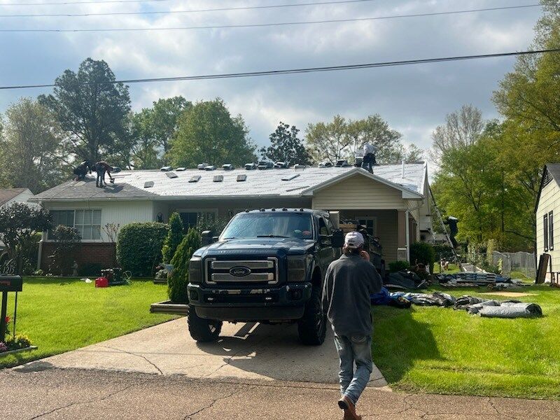 Black pickup truck in a suburban driveway with a person walking toward it on a sunny day