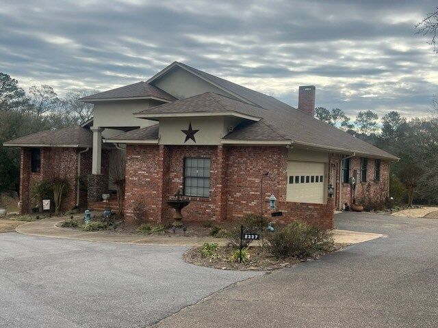 Brick house with a garage, star decoration, and cloudy sky overhead.