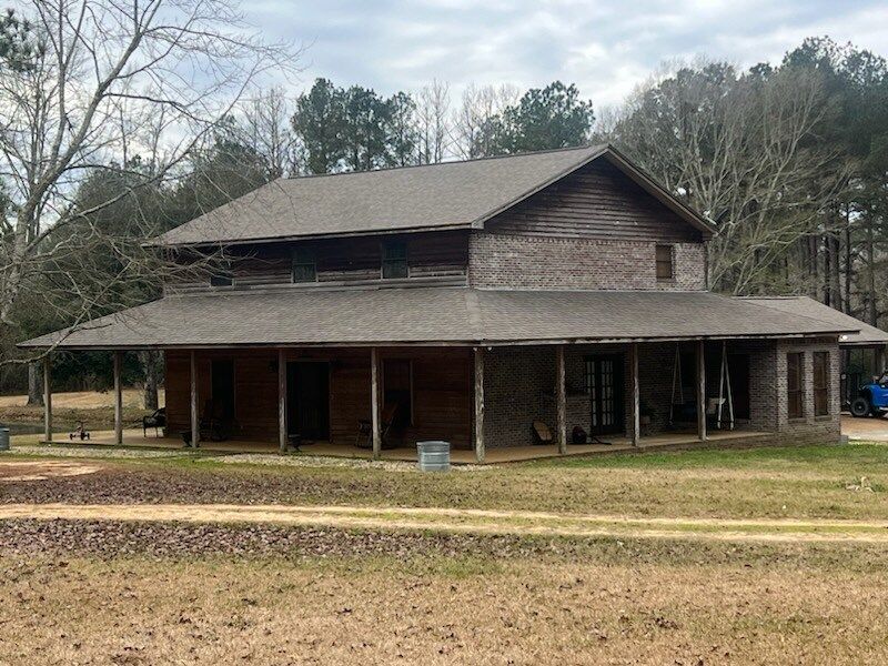Old wooden house with a wraparound porch in a wooded yard