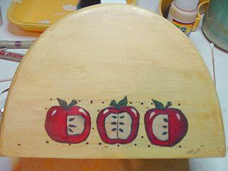 Wooden box with three painted red apples; beige background.