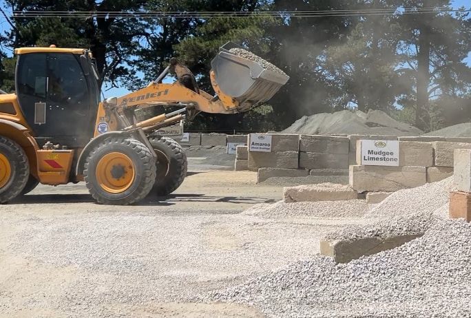 A yellow bulldozer is loading gravel into a bucket — Pigot's Mid Western Sand and Soil In Orange, NSW