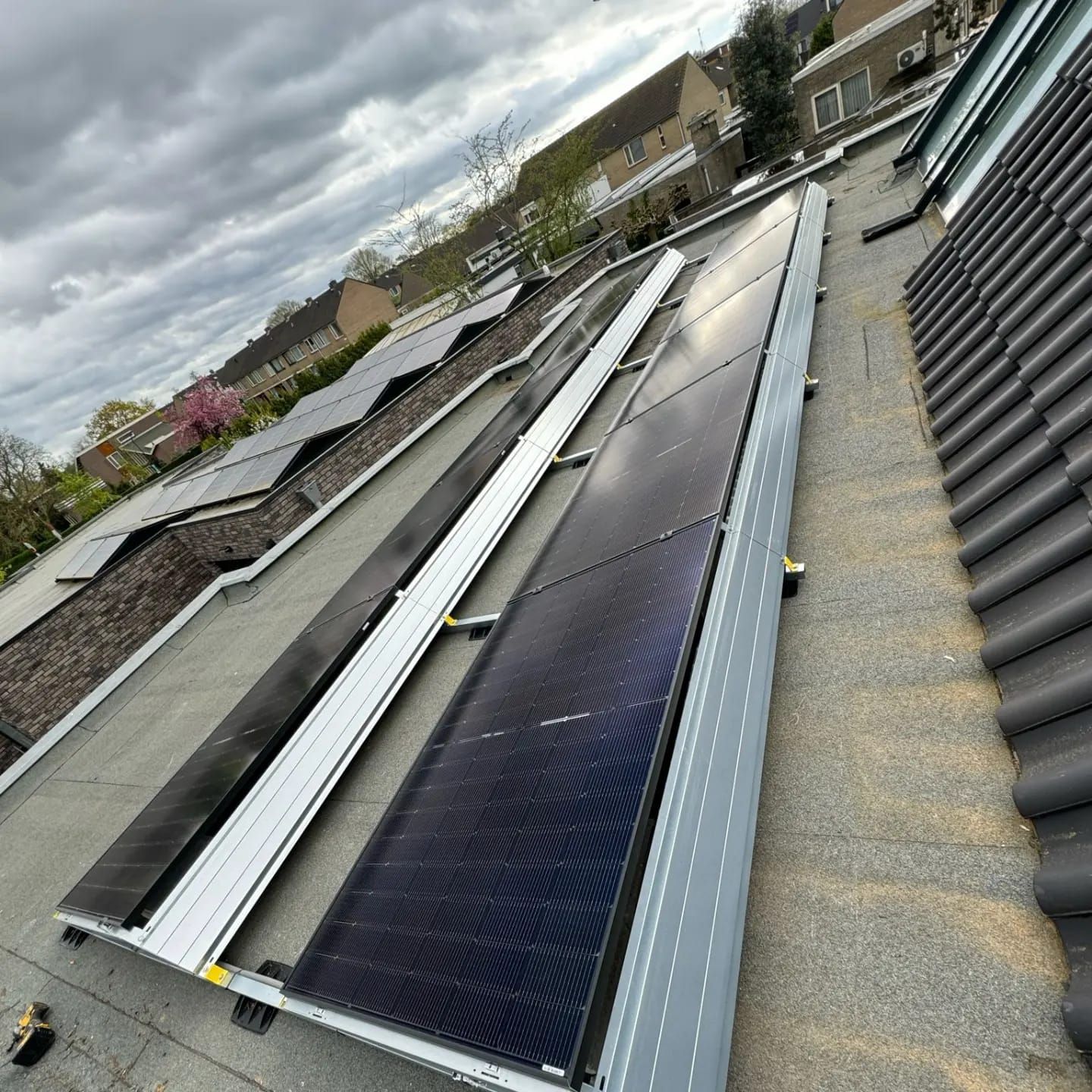 Zonnepanelen geïnstalleerd op een dak tegen een bewolkte hemel.