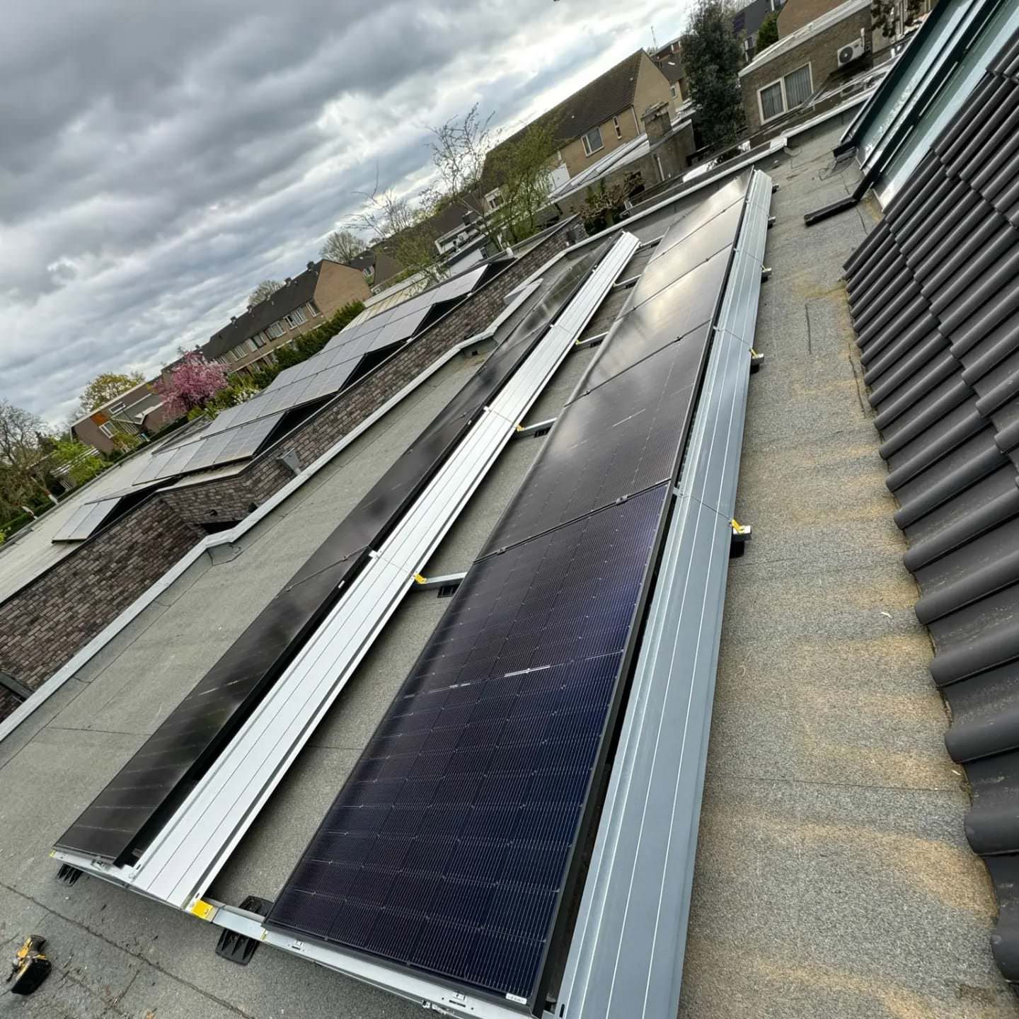 Zonnepanelen geïnstalleerd op een plat dak, bewolkte lucht.